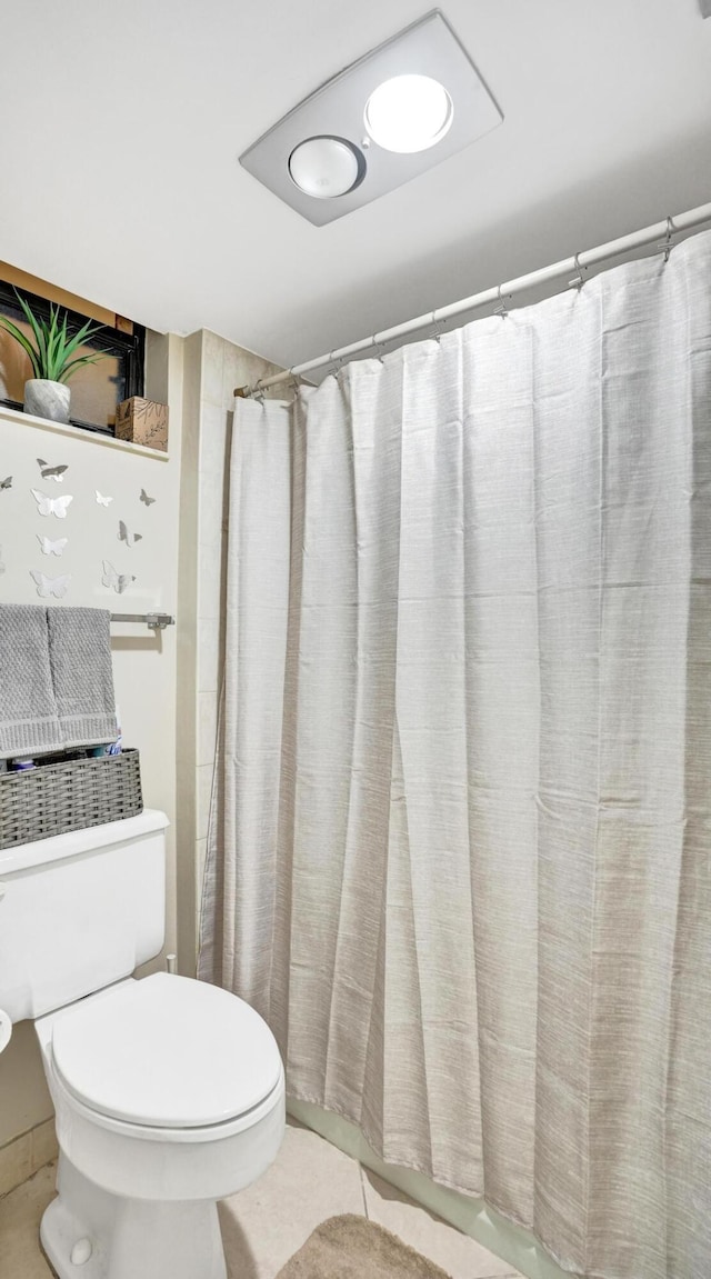 bathroom featuring toilet, a shower with curtain, and tile patterned floors