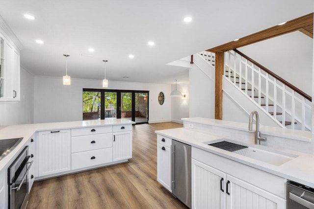 kitchen with light wood-style flooring, stainless steel appliances, a sink, white cabinets, and light countertops