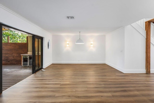 unfurnished room with beverage cooler, visible vents, crown molding, and wood finished floors