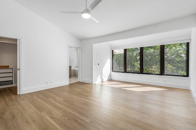 unfurnished bedroom with light wood-type flooring, baseboards, a walk in closet, and lofted ceiling