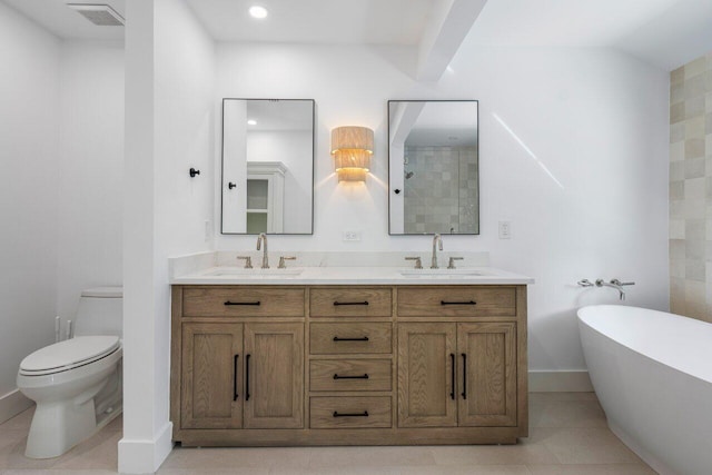 full bathroom with toilet, a freestanding bath, visible vents, and a sink