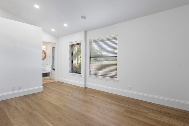 unfurnished room with vaulted ceiling, recessed lighting, light wood-style flooring, and baseboards