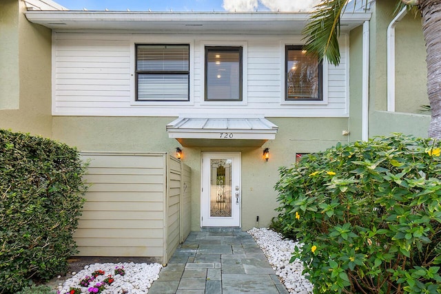 entrance to property featuring a standing seam roof, metal roof, and stucco siding