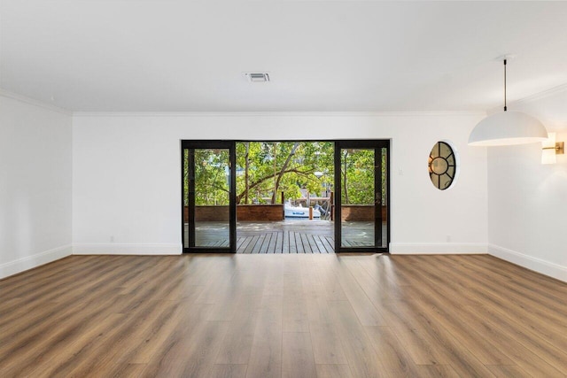 spare room with ornamental molding, visible vents, baseboards, and wood finished floors