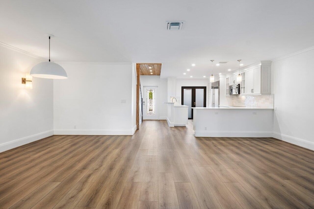 unfurnished living room featuring recessed lighting, wood finished floors, visible vents, baseboards, and crown molding