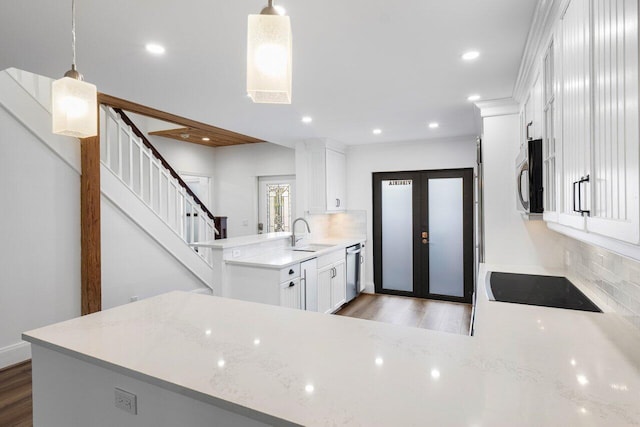 kitchen with backsplash, light wood-style flooring, appliances with stainless steel finishes, a sink, and a peninsula