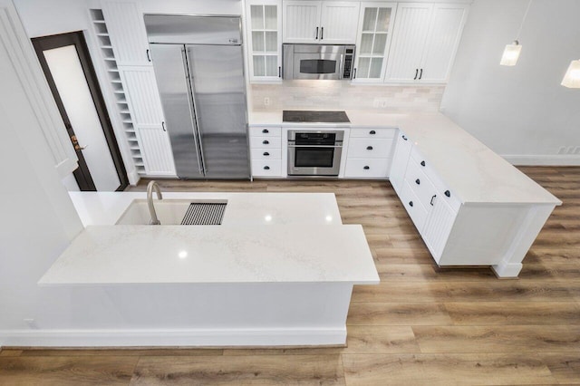 kitchen with a peninsula, light wood-style floors, white cabinetry, and stainless steel appliances