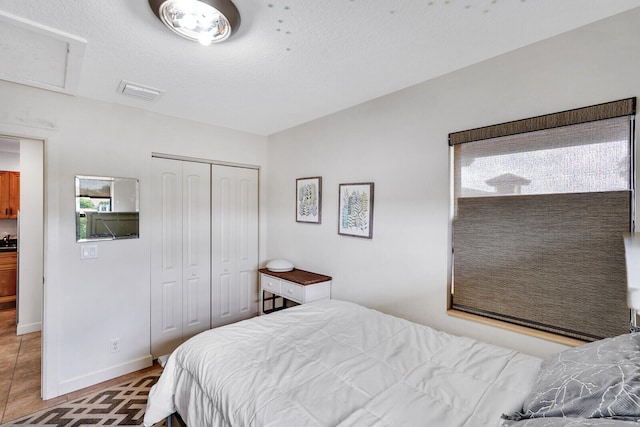 bedroom with a closet, tile patterned flooring, and a textured ceiling