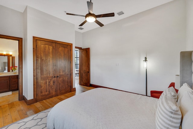 bedroom with ensuite bath, light hardwood / wood-style flooring, ceiling fan, and a closet