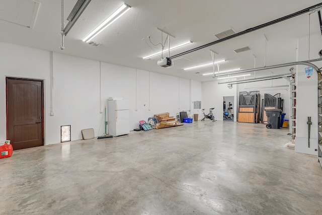 garage with a garage door opener and white fridge