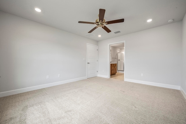 unfurnished bedroom featuring ceiling fan, light carpet, and ensuite bath