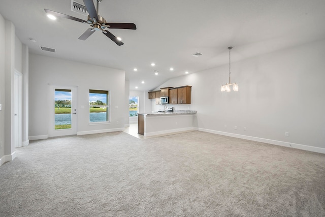 unfurnished living room featuring ceiling fan with notable chandelier, light colored carpet, and lofted ceiling