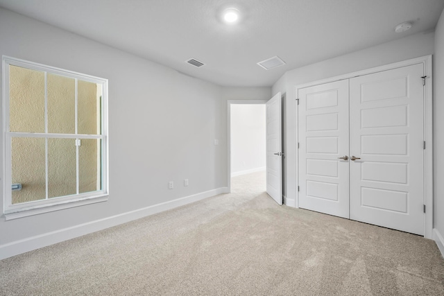 unfurnished bedroom with light colored carpet and a closet