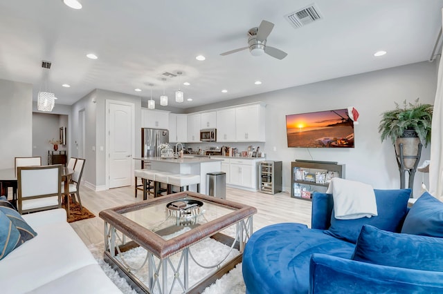 living room featuring light hardwood / wood-style flooring, ceiling fan, and sink