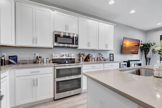 kitchen featuring white cabinets, appliances with stainless steel finishes, and light hardwood / wood-style floors