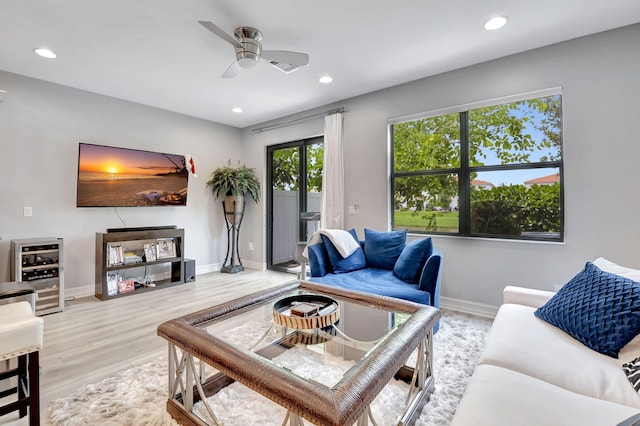 living room featuring beverage cooler, ceiling fan, and light wood-type flooring