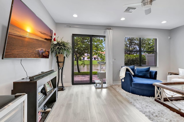 living room featuring a wealth of natural light, ceiling fan, and light wood-type flooring