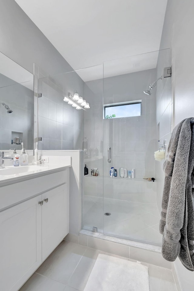 bathroom with a shower with door, vanity, and tile patterned floors