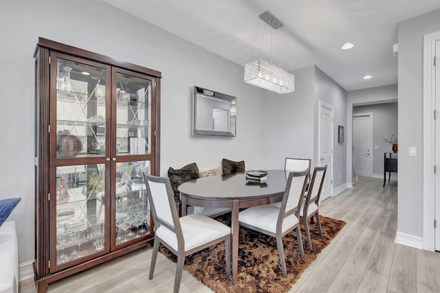 dining space featuring light hardwood / wood-style flooring and a chandelier