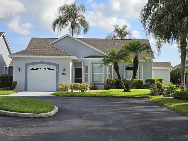 ranch-style home featuring a garage and a front lawn