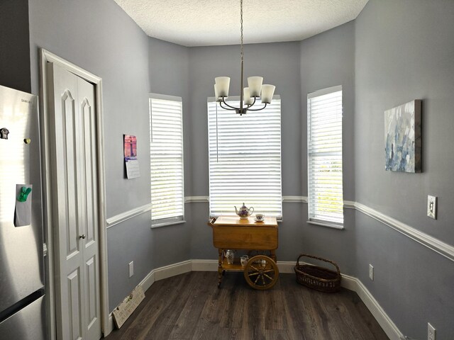 dining space featuring dark hardwood / wood-style flooring, a notable chandelier, and a textured ceiling