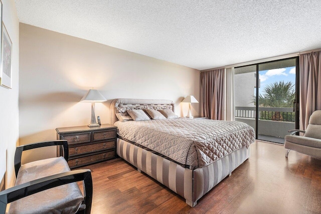 bedroom featuring a wall of windows, access to exterior, dark hardwood / wood-style flooring, and a textured ceiling