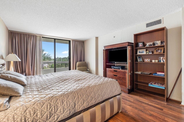 bedroom featuring a textured ceiling, dark hardwood / wood-style floors, and access to outside