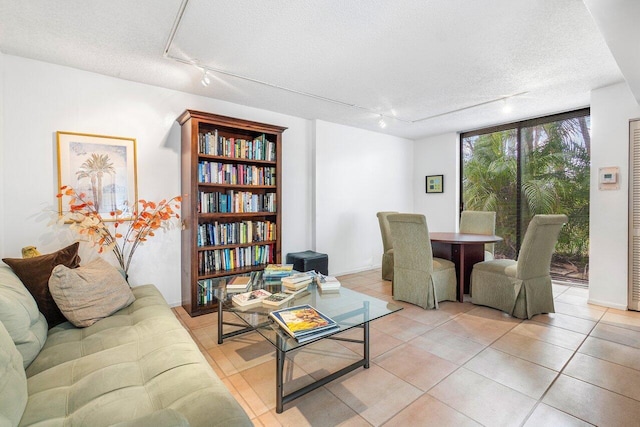 living room with a wall of windows, light tile patterned flooring, a textured ceiling, and rail lighting