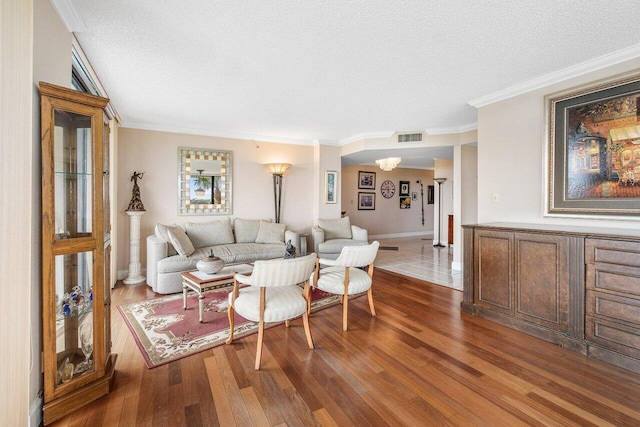 living room with hardwood / wood-style flooring, a textured ceiling, crown molding, and an inviting chandelier