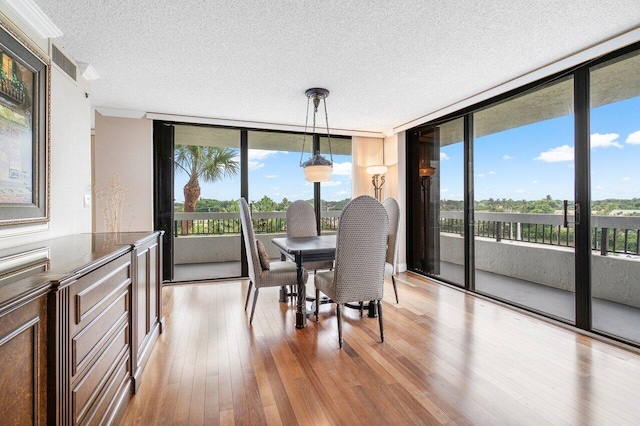 dining space featuring a textured ceiling, floor to ceiling windows, and light hardwood / wood-style floors