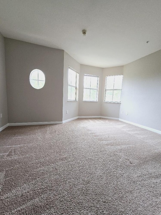 carpeted empty room with a textured ceiling and baseboards