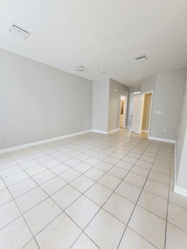 empty room featuring baseboards, visible vents, and a textured ceiling