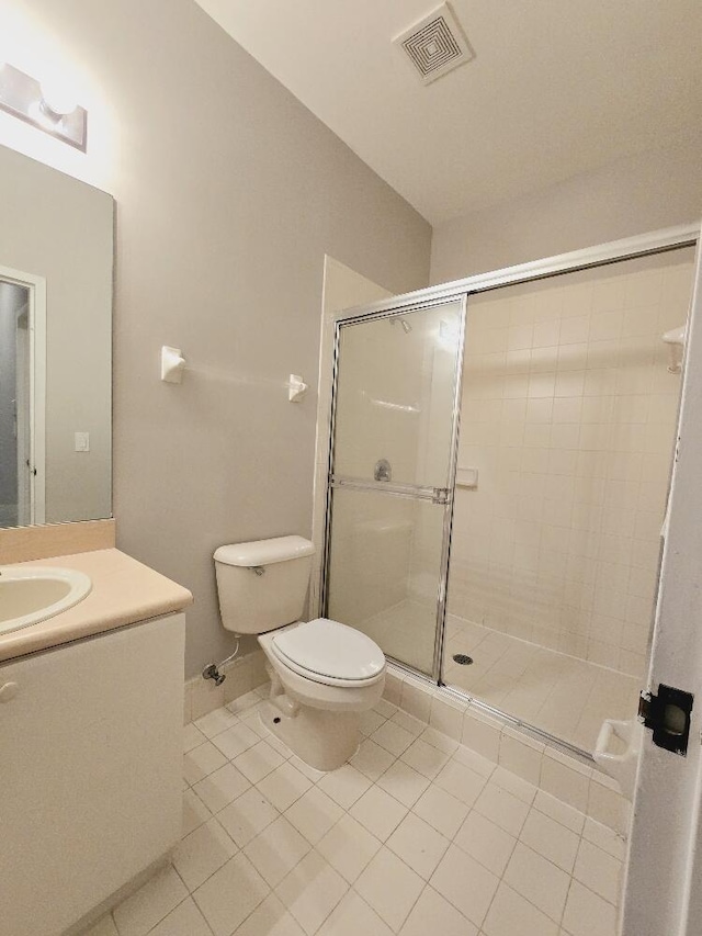 bathroom with a shower with door, toilet, vanity, and tile patterned floors