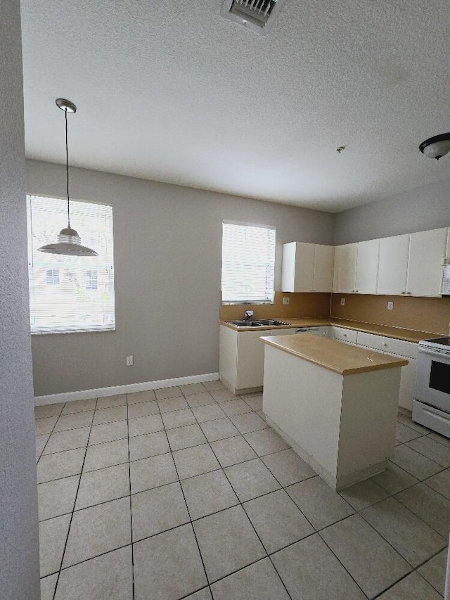 kitchen featuring electric range, white cabinets, a center island, light tile patterned flooring, and hanging light fixtures