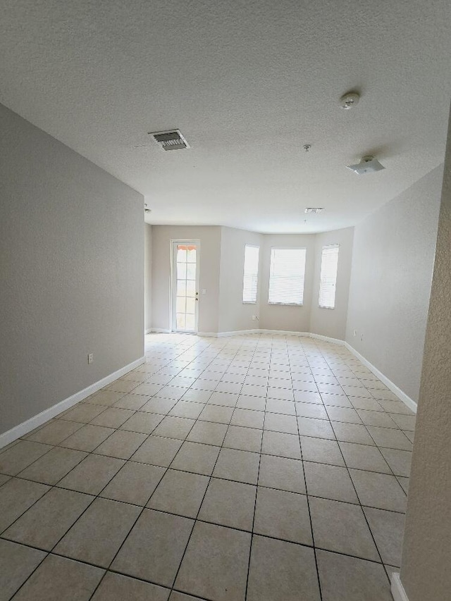 empty room with light tile patterned floors and a textured ceiling