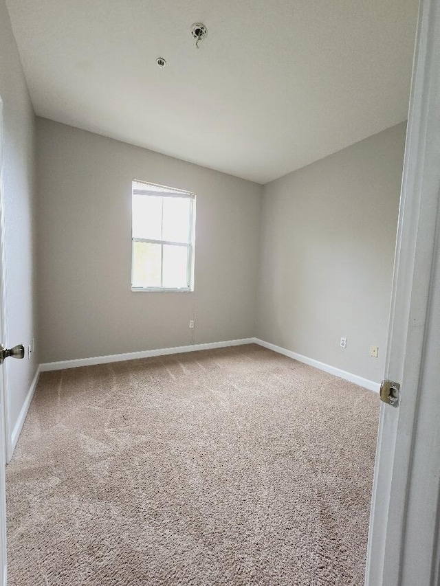 carpeted empty room featuring baseboards