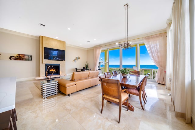 dining space featuring a fireplace, crown molding, and an inviting chandelier