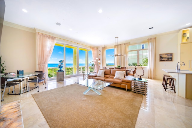 living room featuring ornamental molding, a wealth of natural light, a water view, and a chandelier