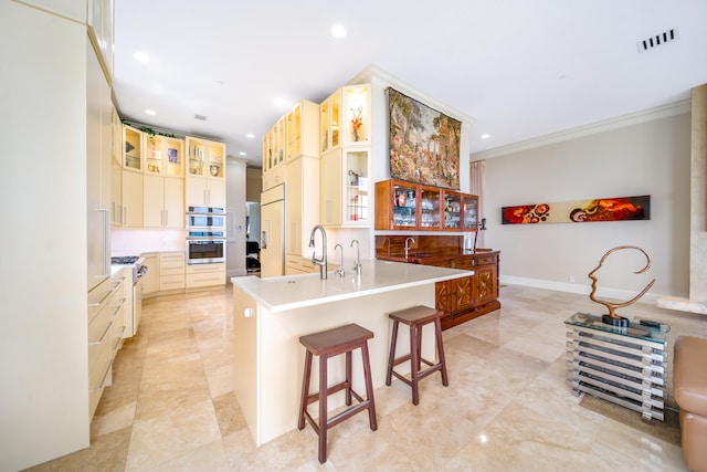 kitchen featuring a kitchen bar, premium appliances, sink, crown molding, and backsplash