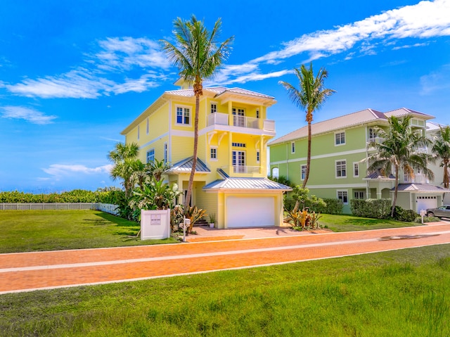 view of front of property with a garage, a balcony, metal roof, a standing seam roof, and a front lawn