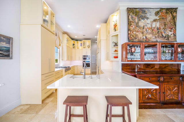 kitchen featuring kitchen peninsula, appliances with stainless steel finishes, sink, and a breakfast bar