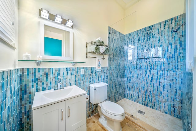 bathroom with toilet, tile patterned floors, tile walls, a tile shower, and vanity