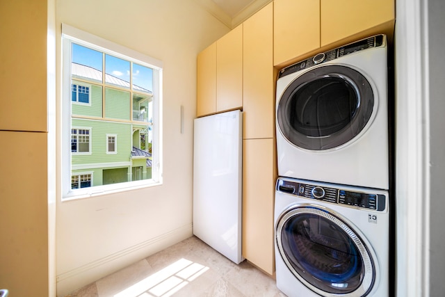 laundry room featuring cabinets, stacked washer and dryer, and ornamental molding