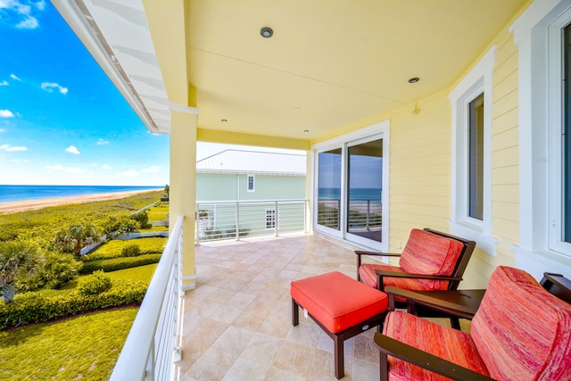 view of patio featuring a water view, a view of the beach, and a balcony