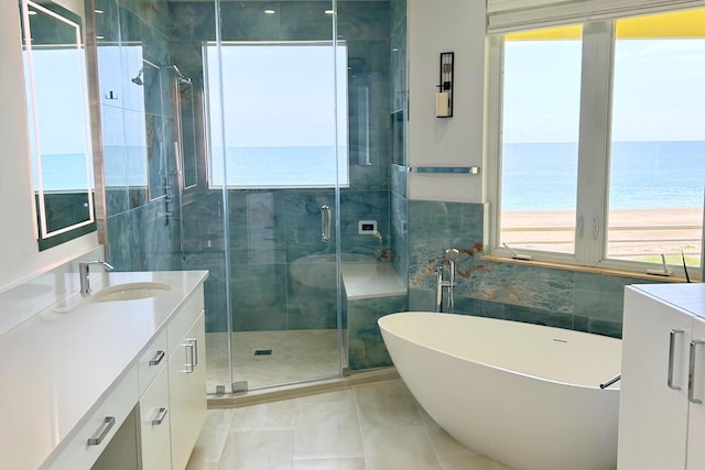 bathroom with tile patterned flooring, a water view, vanity, plus walk in shower, and tile walls