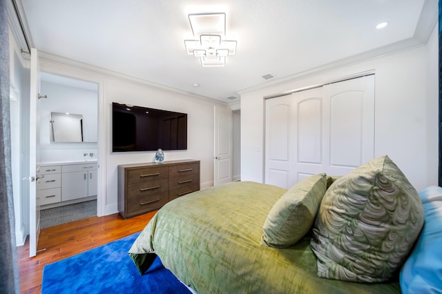 bedroom with connected bathroom, a closet, hardwood / wood-style floors, and ornamental molding