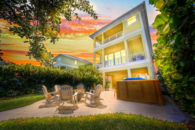 back house at dusk featuring a patio area and a balcony