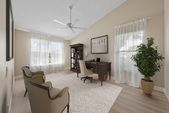 office area featuring ceiling fan, light wood-type flooring, and vaulted ceiling