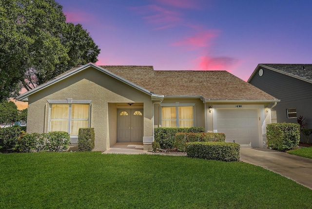 single story home with a garage and a lawn