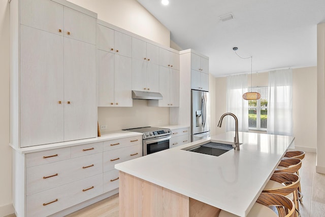 kitchen with a breakfast bar, stainless steel appliances, a center island with sink, and sink